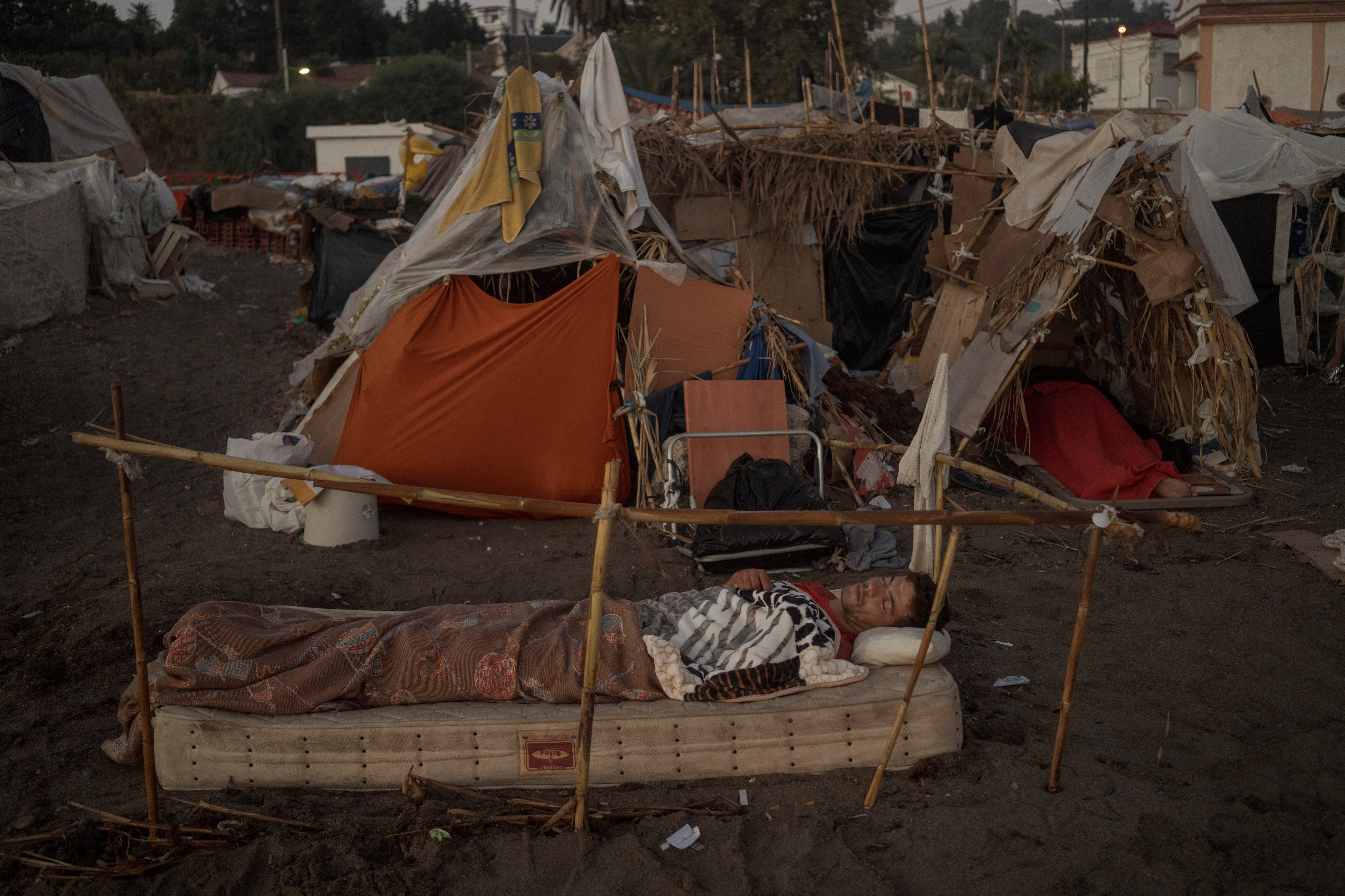 Un hombre duerme en el asentamiento de chabolas de la playa del Trampolín. 
