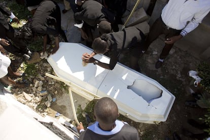 Algunos familiares dañan el ataúd con los restos de un miembro de la familia, justo antes del entierro en el cementerio nacional de Puerto Príncipe, en Haití. Las familias llevan a cabo esta práctica con el fin de evitar que roben el féretro y que el cuerpo termine en el suelo.