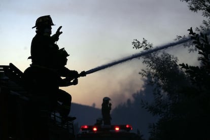 Unos bomberos rocían con agua un bosque en llamas en Valparaíso, Chile, el pasado 14 de marzo. Un grave incendio se expandió con rapidez por la costa chilena y amenazó con alcanzar las ciudades portuarias de Valparaíso y Viña del Mar.