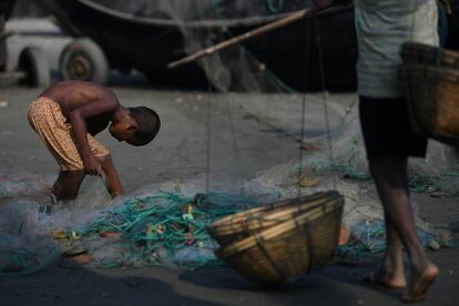 Un niño refugiado rohingya busca restos de comida entre una red de pesca