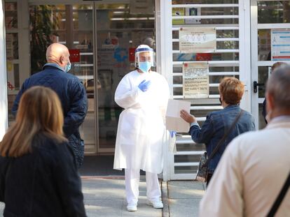 Una sanitaria sale a atender a las personas que hacen cola en un centro de salud en Vicálvaro (Madrid), este lunes.