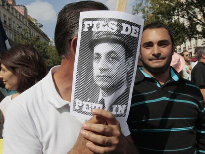 Un manifestante muestra una imagen de Sarkozy, caricaturizado como <i>hijo de Pétain.</i>