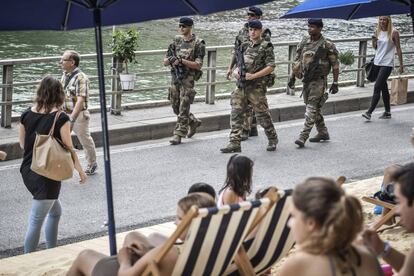 Varios soldados franceses vigilan la &quot;playa&quot; de Par&iacute;s en las orillas del canal del r&iacute;o Sena.