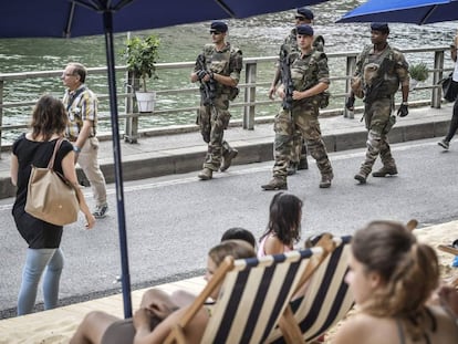 Varios soldados franceses vigilan la &quot;playa&quot; de Par&iacute;s en las orillas del canal del r&iacute;o Sena.