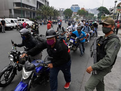 Members of the National Bolivarian Guard control a queue of bikers waiting to refuel their tanks, near a gas station in Caracas on May 25, 2020 amid the novel COVID-19 coronavirus outbreak. (Photo by Federico PARRA / AFP)