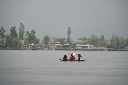 Un barquero de Cachemira transporta a los niños de la escuela en el lago Dal mientras sostienen los paraguas durante la lluvia en Srinagar el 24 de abril de 2019.