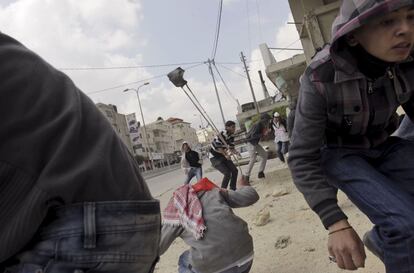 Palestinos lanzan piedras contra las tropas israelíes en el puesto de control de Kalandia.