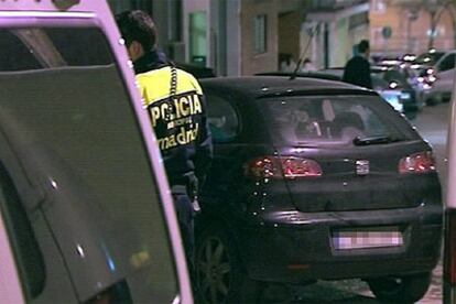 Un agente de la Policía permanece junto al vehículo bajo el cual estaba la bomba, en la calle Palomeras de Madrid.