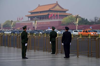 Dois policiais paramilitares e um policial montam guarda em frente à Praça de Tiananmen, em Pequim.