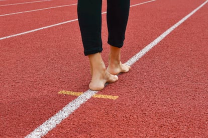 Barefoot on the white line of the red running track