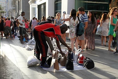 Un inmigrante mantero dispone la mercancía en la Gran Vía de Madrid.