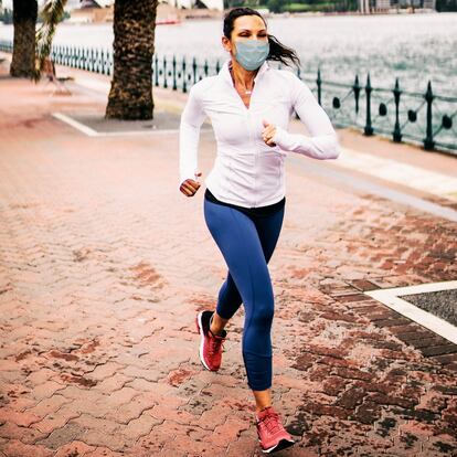 Una mujer corre con una mascarilla.