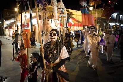 Mujeres y hombres vistiendo el traje regional del valle de Oaxaca desfilan en una comparsa celebrando el Día de Muertos.