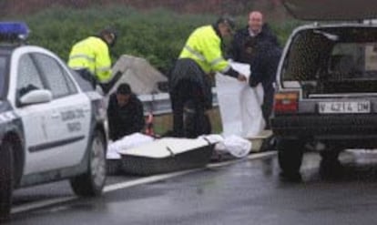 Agentes de la Guardia Civil y empleados de una funeraria, ayer, en el momento de levantar los cadáveres en la autopista.