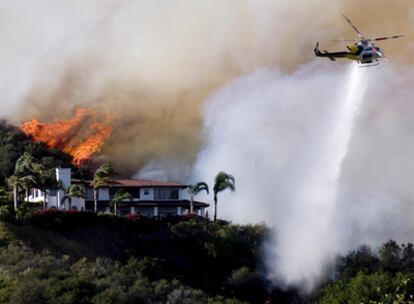 Un helicóptero esparce agua sobre el incendio forestal en Santa Bárbara.