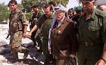 Yasir Arafat, portando una pistola enfundada en su mano izquierda, inspecciona un cuartel palestino destruido por el Ejército israelí en Gaza.
