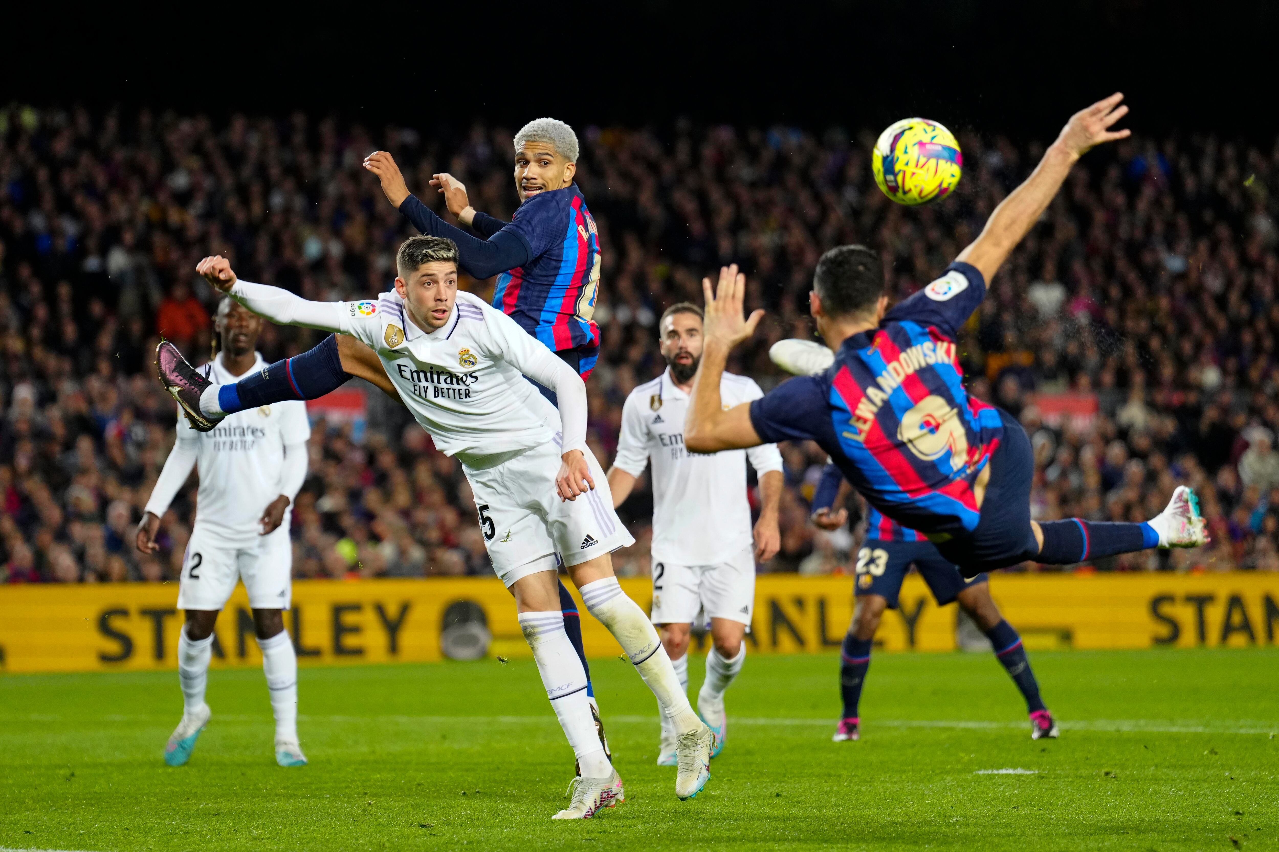 El delantero polaco del Barcelona, Robert Lewandowski (derecha), intenta rematar ante el centrocampista uruguayo del Real Madrid, Fede Valverde.