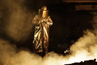 Un empleado con ropa de protección trabaja en un horno de acero, Salzgitter AG, en Alemania.