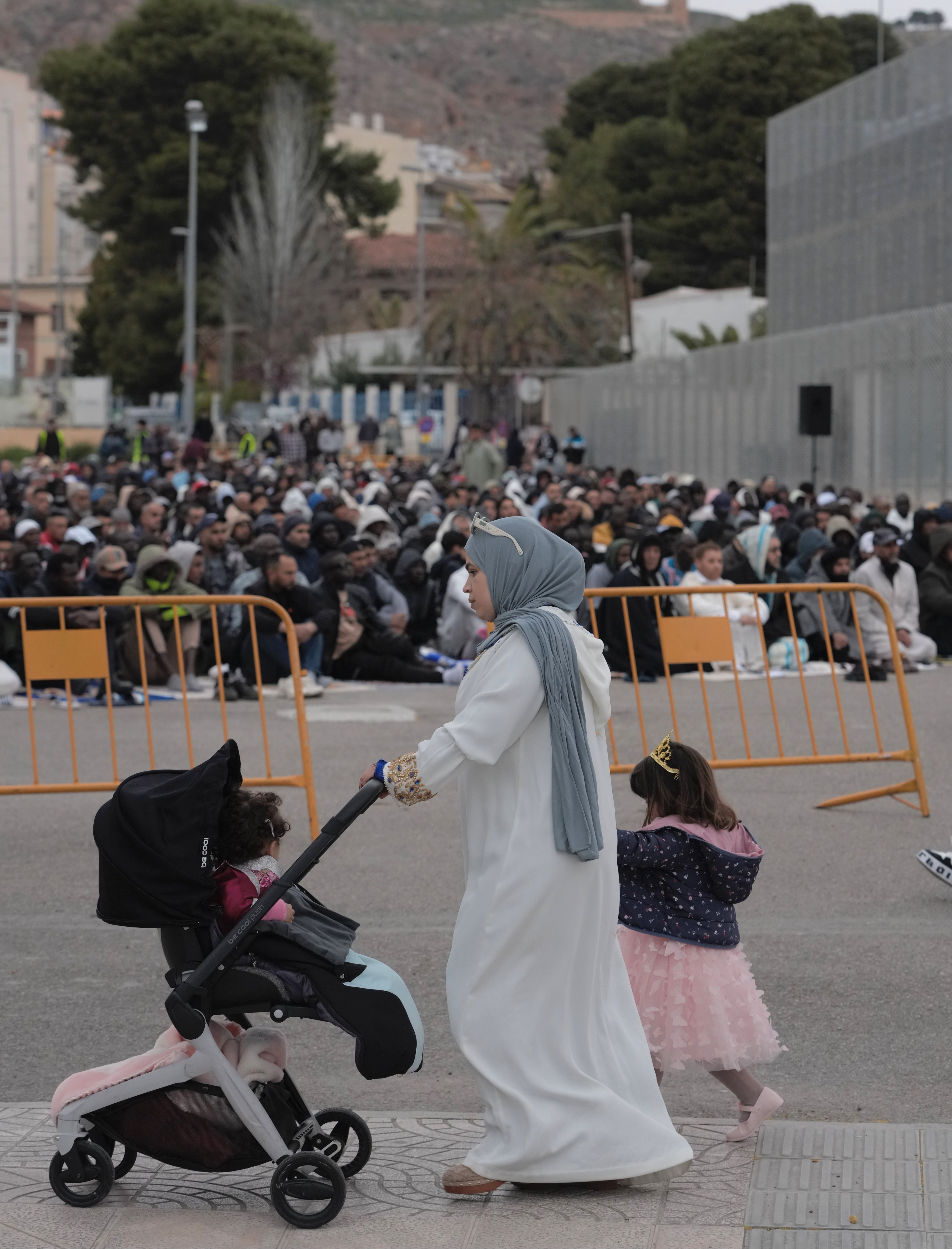 Una mujer pasa, con sus hijos, frente al aparcamiento en el que se ha hecho el rezo. 
