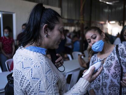 Una mujer se toma la temperatura en un asilo para migrantes de Tijuana.