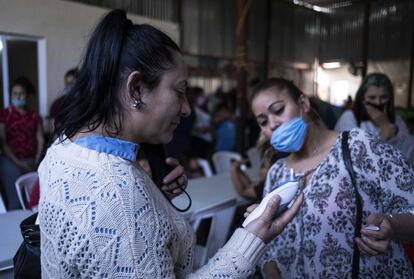 Una mujer se toma la temperatura en un asilo para migrantes de Tijuana.