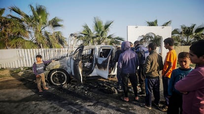 Varias personas observan el estado en el que ha quedado uno de los vehículos de la ONG World Central Kitchen atacados en Gaza.
