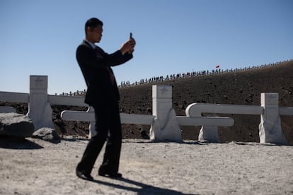 Un guardia de seguridad hace una fotografía mientras un grupo de estudiantes norcoreanos marcha hacia la cima del Monte Baekdu, cerca de Samjiyŏn (Corea del Norte). Cada año, 100.000 norcoreanos o más visitan el Monte Baekdu en viajes de estudio al campamento, la montaña y los sitios revolucionarios cercanos donde se conservan las reliquias de las operaciones.