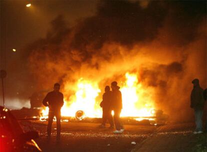 Varios jóvenes se refugian tras una barricada de contenedores ardiendo en la localidad sueca de Malmö.