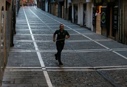 Un pastor corre por la calle Estafeta antes de dar comienzo el quinto encierro de los Sanfermines.