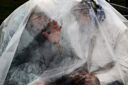 Dos mujeres se cobijan de la lluvia bajo un plástico mientras esperan la llegada del papa Francisco al importante santuario mariano en Anglona, donde celebró una misa, en Letonia.