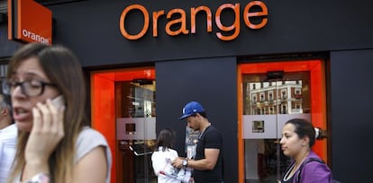 Varias personas junto a una tienda Orange en Madrid. 