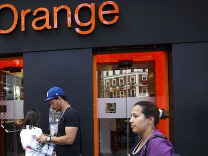 Varias personas junto a una tienda Orange en Madrid. 