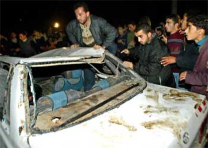 Varios palestinos inspeccionan el interior del coche calcinado donde viajaba el militante de la Yihad asesinado por helicópteros israelíes.