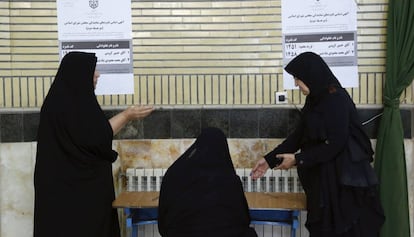 Varias mujeres rellenan sus papeletas en un centro electoral de Shahre Ghods.