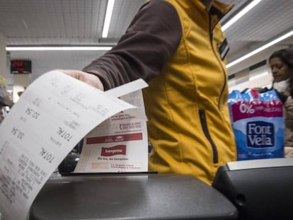 Un caixer de Bon Preu recull un tiquet de compra en un supermercat.