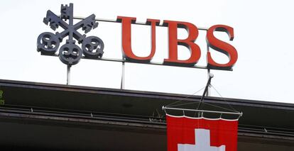 Bandera de suiza bajo el logo de UBS, en Zúrich (Suiza).