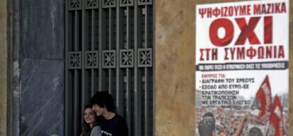 Una pareja junto a un cartel que pide el "no" en el referéndum del domingo, en Atenas