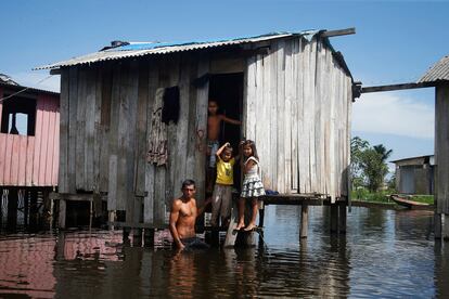 Francisco Fabiano Rodrigues y sus hijos parados en el pórtico de su casa, en Iranduba.