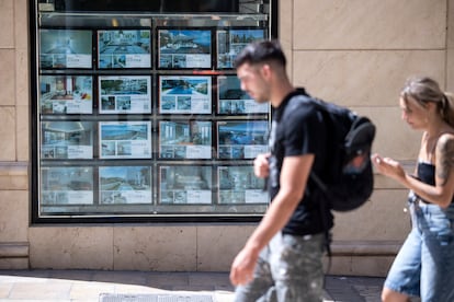 Un hombre y una mujer pasan frente a una inmobiliaria en Málaga, en julio de 2025. 