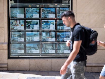 Un hombre y una mujer pasan frente a una inmobiliaria en Málaga, en julio de 2025.