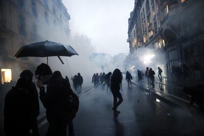 Decenas de personas se cubren del gas lacrimógeno lanzado por la policía durante una manifestación contra la reforma de las pensiones del Gobierno de Emmanuel Macron, este jueves en París (Francia).