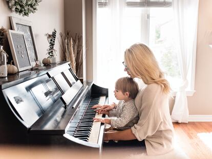 Una madre toca con su hijo el piano.