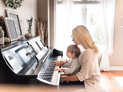 Una madre toca con su hijo el piano.