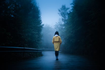 Una mujer camina sola por una carretera.