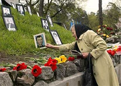 Una mujer coloca el retrato de su hijo junto al monumento, en Kiev, en memoria de las víctimas.