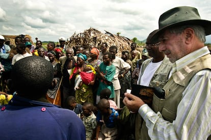Mario Vargas Llosa, toma apuntes para su reportaje junto a unos niños en el campo de desplazados de Hewa Bora, en Congo.