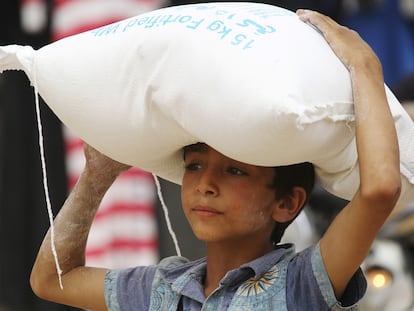 Un niño carga un saco de alimentos entregado por la ONU en la ciudad siria de Raqa.