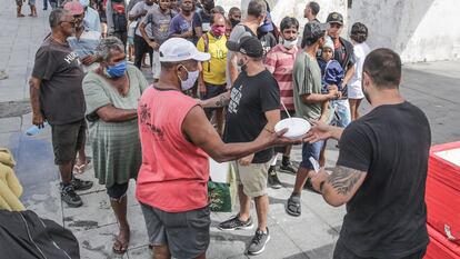 Voluntários entregam marmitas para pessoas em situação de rua, no Rio de Janeiro.