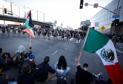Manifestantes se sientan en una avenida cortada por la policía durante la protesta contra las redadas federales de inmigración, esta tarde en el centro de Los Ángeles, California.