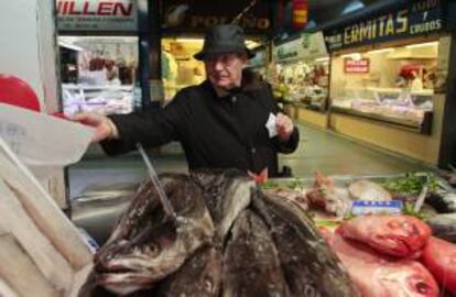 Un hombre coge un número de turno en una pescadería en el mercado de Lugo. EFE/Archivo